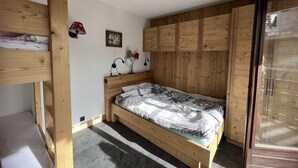 Una camera da letto con un letto a castello, un letto singolo, pannelli di legno sulle pareti, un quadro incorniciato e una lampada.