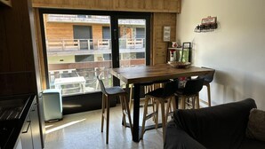Una cucina moderna con zona pranzo, un divano nero e vista del balcone esterno.