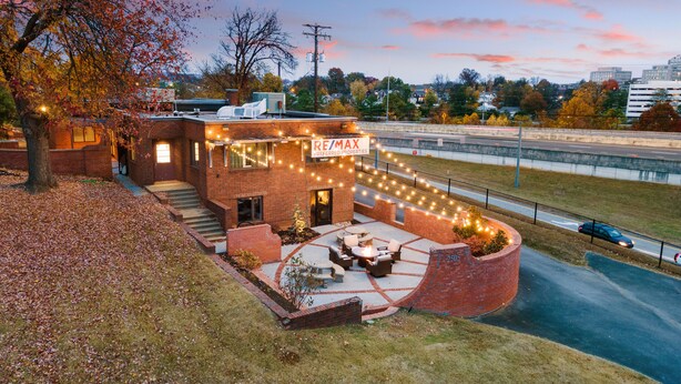 A brick building with a sign reading "RE/MAX Preferred Properties" and outdoor seating with string lights. - Funky, Fun, and Fabulous!!! (Knoxville)