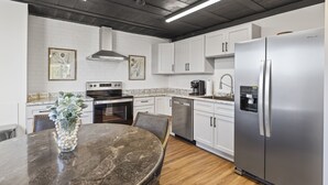 A modern kitchen with white cabinets, stainless steel appliances, and a marble countertop. - Funky, Fun, and Fabulous!!! (Knoxville)