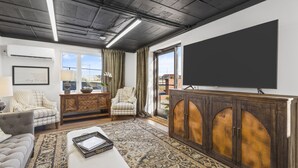 A modern living room with a large flat-screen TV, a patterned rug, and a wooden cabinet. - Funky, Fun, and Fabulous!!! (Knoxville)