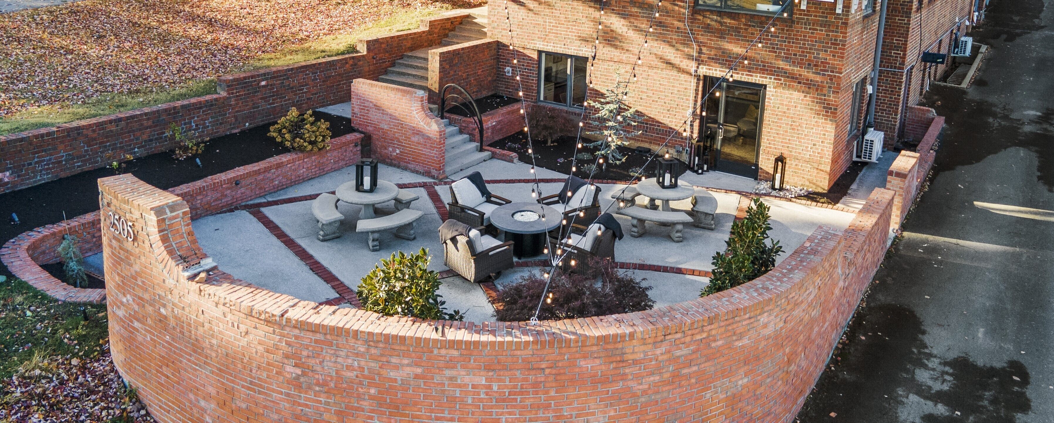 A circular brick patio with outdoor seating and a fire pit.