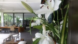 Ein modernes Interieur mit einer Sitzecke, einer Glaswand und weißen Lilien.