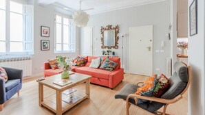 A bright living room with a red sofa, a wooden coffee table, and a gray armchair.