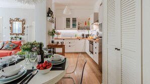 A modern kitchen with white cabinetry, a wooden countertop, and a dining area with a table set for two.
