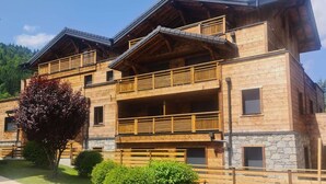Un edificio in legno a più piani con balconi, dettagli in pietra e un giardino curato.