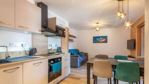 Una cucina moderna con forno integrato, macchina del caffè e zona pranzo con tavolo e sedie.