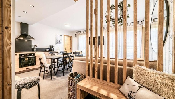 Un interior modern amb una cadira de fusta, una zona de menjador i una cuina.