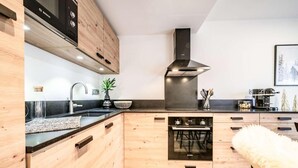 Cuina moderna amb armaris de fusta, forn Bosch i campana extractora negra.