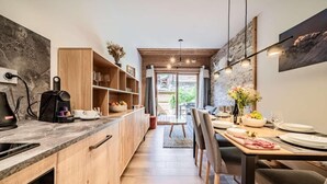 A modern kitchen with wooden cabinets, a built-in coffee machine, and a dining area with a table set for two.