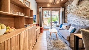 A modern living room with a wooden reception desk, a grey sofa, and a stone wall.