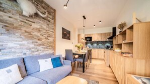 A modern living room with a grey sofa, a wooden coffee table, and a stone wall.