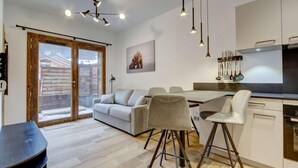 A modern kitchen with a dining area, a sofa, and a bar stool. - 140m from ski lifts, balcony, tv, 27m², Morzine (Morzine)