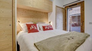 A bedroom with a wooden headboard, white bedding, and red pillows. - 140m from ski lifts, balcony, tv, 27m², Morzine (Morzine)
