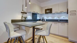 A modern kitchen with a central island, two grey chairs, hanging lights, and white cabinetry. - 140m from ski lifts, balcony, tv, 27m², Morzine (Morzine)