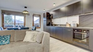 A modern kitchen with dark cabinets, a built-in oven, and a large window.