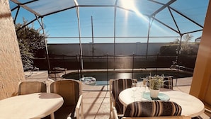 Une terrasse extérieure dotée d’une véranda en verre, comprenant des tables et des chaises, une piscine et une vue sur les environs.