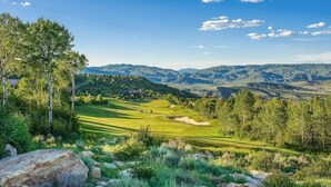 Un campo de golf con vistas despejadas del paisaje circundante, incluyendo colinas y árboles.
