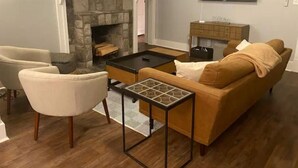 Ein Wohnzimmer mit Kamin aus Stein, einer Couch, einem Couchtisch und einem an der Wand befestigten Fernseher.