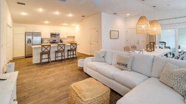 A modern kitchen with white cabinets, a central island with bar stools, and a ceiling fan. - Golfer's Paradise: Pet-Friendly Home in Wildwood (Wildwood)