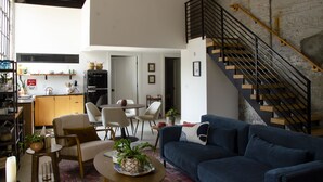 Una sala de estar moderna con un sofá azul, una mesa de centro y una escalera con barandilla de metal.