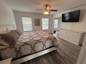Relax in this inviting bedroom with a large bed, ceiling fan, and flat-screen TV.