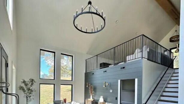 A modern kitchen with a large island, wooden cabinets, and a built-in oven. There is a dining area with a table and chairs, and a staircase leading to an upper level. - Cottage at the Ridge#2-40 min south of Nashville (Spring Hill)