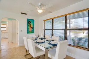 A dining area with a glass table, white chairs, and a ceiling fan. - Dock, Grill & Pool: Waterfront Cape Coral Home! (Cape Coral)