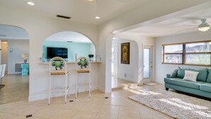 A spacious living area with a teal sofa, white armchairs, and a fluffy rug.