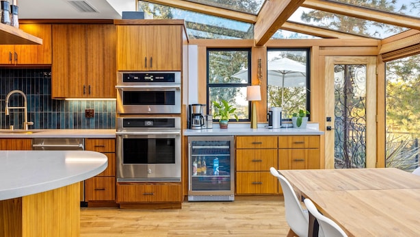 Une cuisine moderne avec des meubles en bois, des appareils électroménagers en acier inoxydable et un réfrigérateur à porte en verre.