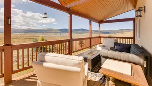 A covered outdoor seating area with a view of a desert landscape, a fire pit, and a wooden table. - Hot Tub & Fire Pit: Idyllic Getaway in Angel Fire! (Angel Fire)