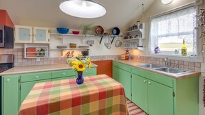 Una cocina con armarios verdes, mantel a cuadros y un jarrón con girasoles.