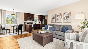Un salon moderne avec un canapé, un pouf et un coin repas.