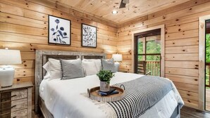 A wooden cabin bedroom with a bed, nightstands, and a ceiling fan. - NEW BUILD SEPT 2023 4 KINGS 1Q BUNK HOT TUB GAME ROOM THEATER  (Pigeon Forge)