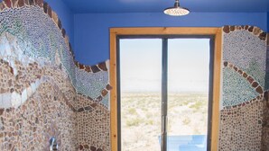A room with mosaic walls, a wooden floor, and a large window with a view of a desert landscape. - Secluded Desert House-Stargazing (Ridgecrest)
