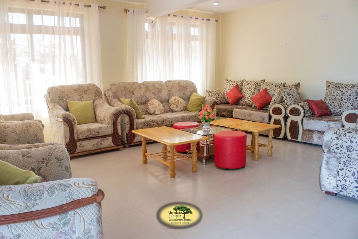 A living room with a sofa set, a wooden coffee table, and red ottomans.