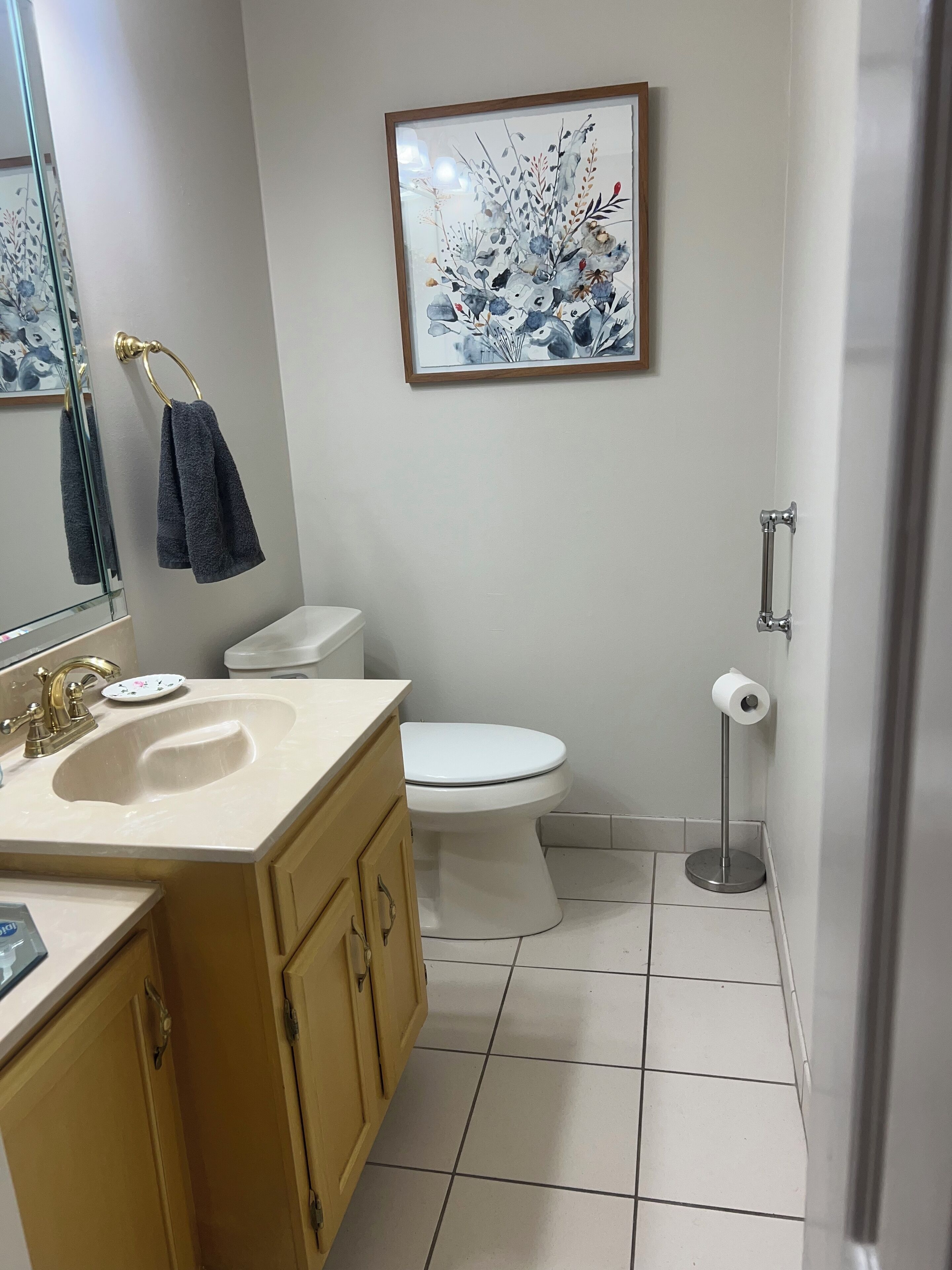 A bathroom with a sink, toilet, and a framed floral artwork on the wall.