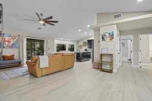 A spacious living area with a sofa, a ceiling fan, and a kitchen in the background. - The Zane Grey Getaway (Payson)