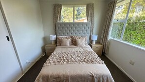 Une chambre à coucher avec un grand lit, deux tables de chevet et une fenêtre avec des rideaux.