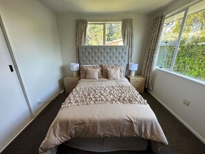 Ein Schlafzimmer mit einem großen Bett, zwei Nachttischen und einem Fenster mit Vorhängen.