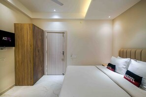 A hotel room with a bed, a wardrobe, a television, and a door. - Aceotel Xpress Mint (Indore)