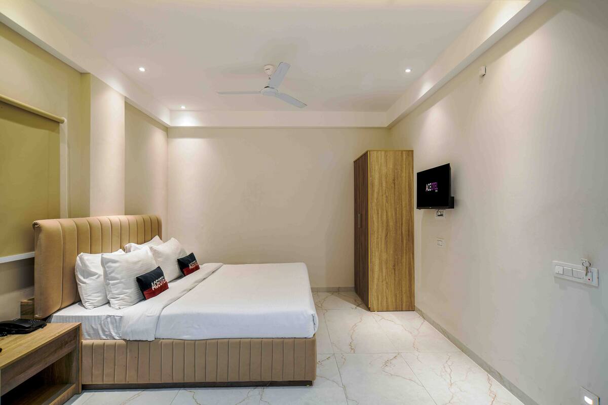 Un dormitorio con cama, armario de madera, televisor montado en la pared y ventilador de techo.