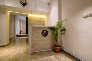 A reception area with a wooden reception desk, a potted plant, and a sign with the logo "ACEOTEL". - Aceotel Xpress Mint (Indore)