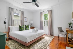 A bedroom with a bed, a desk, a chair, and a ceiling fan.
