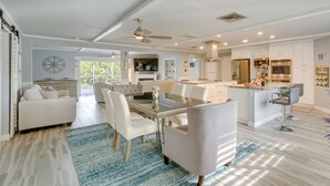 A spacious living area with a dining table, chairs, and a sofa. There is a kitchen with modern appliances and a bar area. - Sarasota Home w/ Pool: 4 Mi to Siesta Key Beach! (Sarasota)