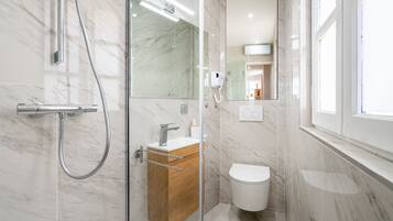 Une salle de bain moderne avec une douche à parois de verre, un meuble-lavabo en bois, des toilettes et un grand miroir.