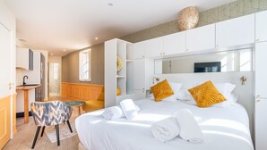 Una habitación de hotel moderna con una cama grande, una pequeña zona de estar, una kitchenette y un baño.