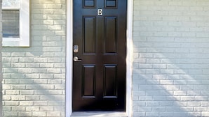 A black door with a keypad lock and a small window above it.