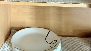A wooden shelf with clear glass bottles and a white ceramic plate.