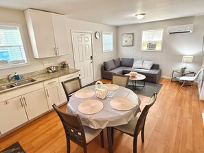 Un espacio habitable compacto con comedor, kitchenette y zona de estar.
